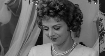 Movie still from “The Visit” (1964), directed by Bernhard Wicki – A person wearing a necklace; Close Up shot, Over the shoulder angle