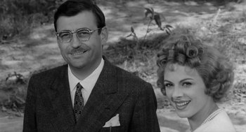 Movie still from “The Visit” (1964), directed by Bernhard Wicki – An older man and a younger woman standing next to each other; Close Up shot, Low angle