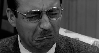 Movie still from “The Visit” (1964), directed by Bernhard Wicki – An older man wearing glasses and a suit; Close Up shot, Low angle