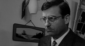 Movie still from “The Visit” (1964), directed by Bernhard Wicki – A black and white photo of a man in a suit; Close Up shot, Low angle