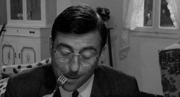 Movie still from “The Visit” (1964), directed by Bernhard Wicki – A black and white photo of a man with a fork in his mouth; Close Up shot, High angle