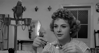 Movie still from “The Visit” (1964), directed by Bernhard Wicki – A black and white photo of a woman holding a fork; Close Up shot, Over the shoulder angle