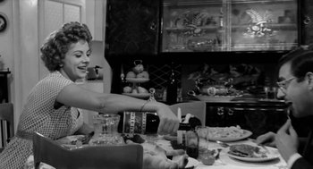 Movie still from “The Visit” (1964), directed by Bernhard Wicki – A black and white photo of a woman at a dinner table; Medium shot, Low angle