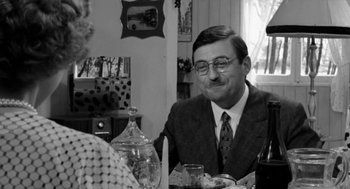 Movie still from “The Visit” (1964), directed by Bernhard Wicki – An older man sitting at a table with a glass of wine; Medium shot, Over the shoulder angle