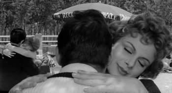 Movie still from “The Visit” (1964), directed by Bernhard Wicki – A man and a woman hugging under an umbrella; Close Up shot, Over the shoulder angle