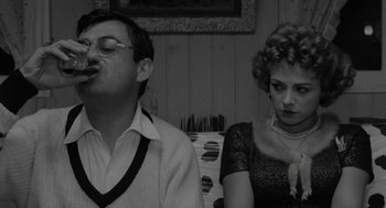 Movie still from “The Visit” (1964), directed by Bernhard Wicki – A man and a woman sitting next to each other in a room; Medium shot, Over the shoulder angle