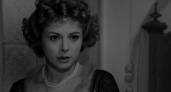 Movie still from “The Visit” (1964), directed by Bernhard Wicki – A black and white photo of a woman in a dress; Close Up shot, Over the shoulder angle