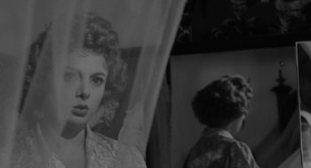 Movie still from “The Visit” (1964), directed by Bernhard Wicki – A black - and - white photo of a woman in front of a mirror; Close Up shot, Low angle