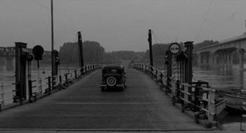 Movie still from “The Visit” (1964), directed by Bernhard Wicki – An old car is driving down a bridge; Extreme Wide shot, High angle