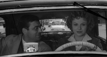 Movie still from “The Visit” (1964), directed by Bernhard Wicki – A man and a woman sitting in the back seat of a car; Medium shot, Over the shoulder angle