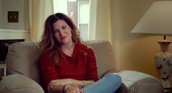 Movie still from “The Visit” (2015), directed by M. Night Shyamalan – A woman sitting on a couch in front of a window; Medium shot, Over the shoulder angle