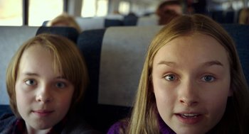 Movie still from “The Visit” (2015), directed by M. Night Shyamalan – Two young girls sitting on a train looking at the camera; Close Up shot, Over the shoulder angle