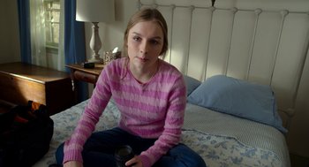 Movie still from “The Visit” (2015), directed by M. Night Shyamalan – A woman sitting on a bed holding a coffee mug; Medium shot, High angle