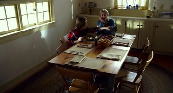 Movie still from “The Visit” (2015), directed by M. Night Shyamalan – Two people sitting at a wooden table with a bowl of fruit; Medium shot, High angle
