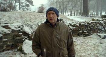 Movie still from “The Visit” (2015), directed by M. Night Shyamalan – A man in a brown jacket and a blue hat holding an axe; Medium shot, Over the shoulder angle