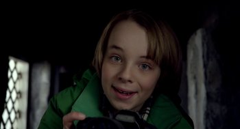 Movie still from “The Visit” (2015), directed by M. Night Shyamalan – A young boy holding a camera in a dark room; Close Up shot, High angle