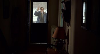 Movie still from “The Visit” (2015), directed by M. Night Shyamalan – A man waving at the camera from a doorway; Wide shot, Over the shoulder angle
