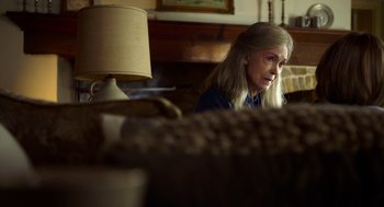 Movie still from “The Visit” (2015), directed by M. Night Shyamalan – A woman sitting at a table in a room with a lamp; Close Up shot, Over the shoulder angle