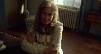 Movie still from “The Visit” (2015), directed by M. Night Shyamalan – An older woman sitting on the floor with her arms crossed; Close Up shot, High angle