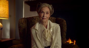 Movie still from “The Visit” (2015), directed by M. Night Shyamalan – An older woman sitting in a chair wearing a sweater; Close Up shot, Over the shoulder angle