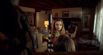 Movie still from “The Visit” (2015), directed by M. Night Shyamalan – A young girl is looking at a mirror in a living room; Medium shot, Over the shoulder angle