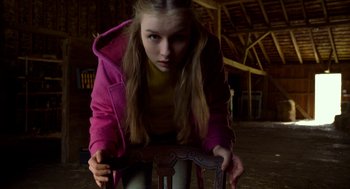 Movie still from “The Visit” (2015), directed by M. Night Shyamalan – A young girl in a pink coat is holding a chair; Medium shot, High angle