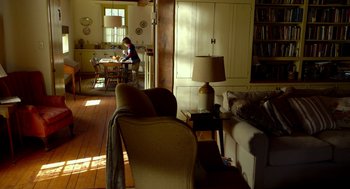 Movie still from “The Visit” (2015), directed by M. Night Shyamalan – A woman sitting at a table in a living room; Wide shot, High angle