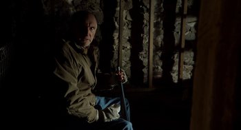Movie still from “The Visit” (2015), directed by M. Night Shyamalan – A man sitting in a dark room holding an umbrella; Medium shot, Low angle