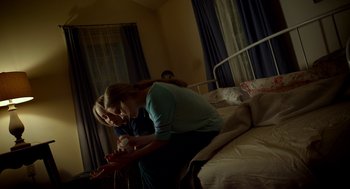 Movie still from “The Visit” (2015), directed by M. Night Shyamalan – A woman sitting on top of a bed next to a man; Medium shot, High angle