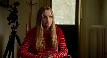 Movie still from “The Visit” (2015), directed by M. Night Shyamalan – A woman sitting in a chair wearing a red sweater; Medium shot, Over the shoulder angle