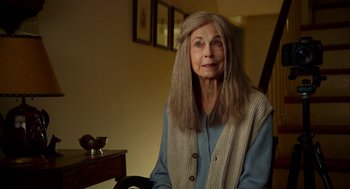 Movie still from “The Visit” (2015), directed by M. Night Shyamalan – An older woman sitting in a chair in a living room; Close Up shot, Over the shoulder angle