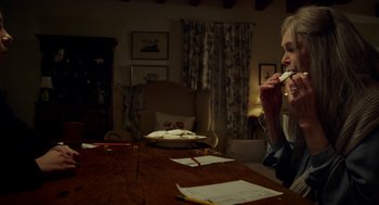 Movie still from “The Visit” (2015), directed by M. Night Shyamalan – A person sitting at a table with papers on the table; Medium shot, Over the shoulder angle