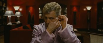 Movie still from “The Walker” (2007), directed by Paul Schrader – A man in a suit adjusting his ear buds; Close Up shot, Over the shoulder angle