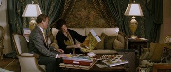 Movie still from “The Walker” (2007), directed by Paul Schrader – A woman sitting on top of a couch looking at papers; Medium shot, High angle