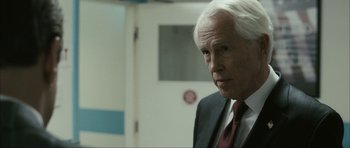 Movie still from “The Walker” (2007), directed by Paul Schrader – An older man wearing a suit and tie in a room; Close Up shot, Over the shoulder angle