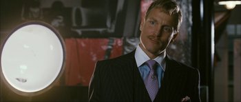 Movie still from “The Walker” (2007), directed by Paul Schrader – A man in a suit and tie standing in front of a wall; Close Up shot, Over the shoulder angle