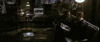 Movie still from “The Walker” (2007), directed by Paul Schrader – A man sitting on top of a couch reading a book; Wide shot, High angle