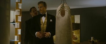 Movie still from “The Walker” (2007), directed by Paul Schrader – A man in a tuxedo standing in front of a punching bag; Medium shot, Low angle