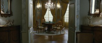 Movie still from “The Walker” (2007), directed by Paul Schrader – A dining room with a round table and a chandelier; Wide shot, High angle
