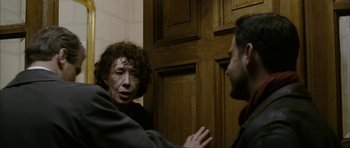 Movie still from “The Walker” (2007), directed by Paul Schrader – A man and a woman talking in front of a wooden door; Medium shot, Over the shoulder angle