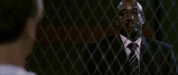 Movie still from “The Walker” (2007), directed by Paul Schrader – A man in a suit and tie behind a chain link fence; Close Up shot, Low angle
