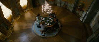 Movie still from “The Walker” (2007), directed by Paul Schrader – A group of people sitting around a table playing cards; Wide shot, Overhead angle