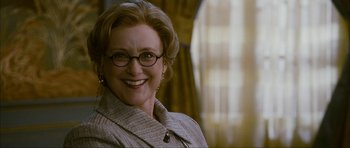 Movie still from “The Walker” (2007), directed by Paul Schrader – An older woman wearing glasses and smiling for the camera; Close Up shot, Low angle