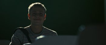 Movie still from “The Wave” (2008), directed by Dennis Gansel – A young man smiling for the camera in the dark; Close Up shot, Low angle