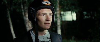 Movie still from “The Wave” (2008), directed by Dennis Gansel – A man wearing a motorcycle helmet in a forest; Close Up shot, Low angle