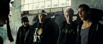 Movie still from “The Wave” (2008), directed by Dennis Gansel – Two young men standing next to each other in front of a brick wall; Medium shot, Low angle