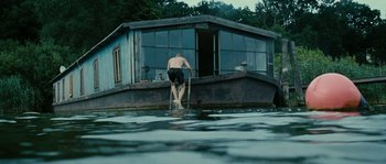 Movie still from “The Wave” (2008), directed by Dennis Gansel – A man standing on the edge of a house boat; Extreme Wide shot, Low angle