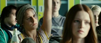 Movie still from “The Wave” (2008), directed by Dennis Gansel – A woman sitting in front of a man holding her arm up in the air; Close Up shot, Over the shoulder angle