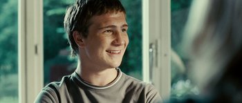 Movie still from “The Wave” (2008), directed by Dennis Gansel – A young man smiles while sitting in front of a window; Close Up shot, Over the shoulder angle