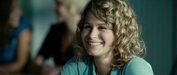 Movie still from “The Wave” (2008), directed by Dennis Gansel – A person with curly hair smiling; Close Up shot, Over the shoulder angle